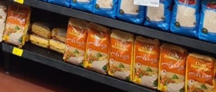 Bottom shelf with orange Don Bernardo rice bags; two bags in between are turned around, showing their pale yellow backs